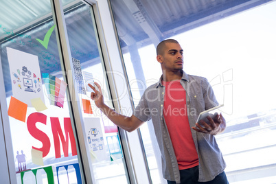 Male executive standing near glass door holding digital tablet