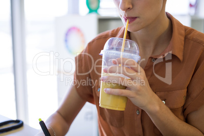 Female executive having drink while working at her desk