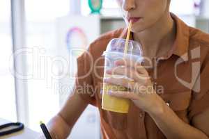 Female executive having drink while working at her desk