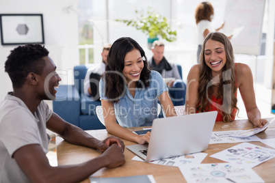 Business colleagues discussing over laptop in the office