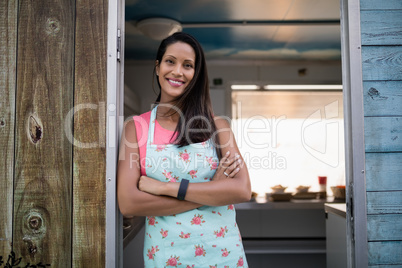 Portrait of happy waitress standing with arms crossed