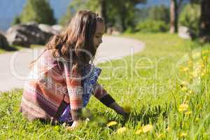 Cute girl plucking flower from field