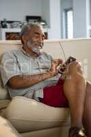 Senior man using mobile phone in the living room