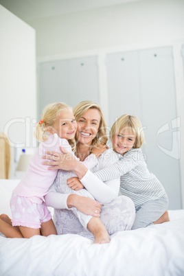 Portrait of smiling kids embracing her mother in bedroom