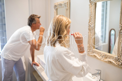 Couple brushing teeth in front of mirror