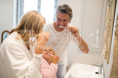 Parents and daughter brushing teeth in bathroom