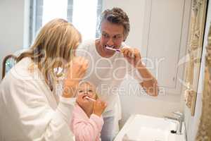 Parents and daughter brushing teeth in bathroom