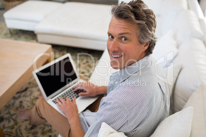 Smiling man using laptop in living room