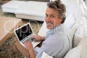 Smiling man using laptop in living room