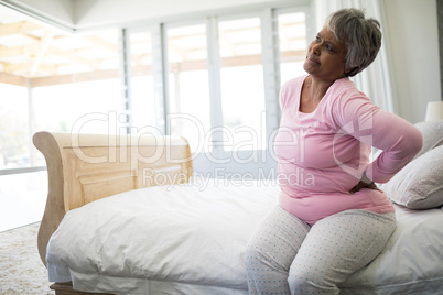 Senior woman having back pain in bedroom