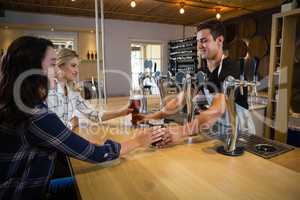 Bartender serving drinks to female friends