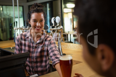 Smiling barmaid serving drink to man