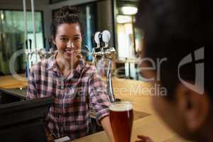 Smiling barmaid serving drink to man