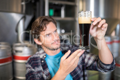 Worker examining beer in glass