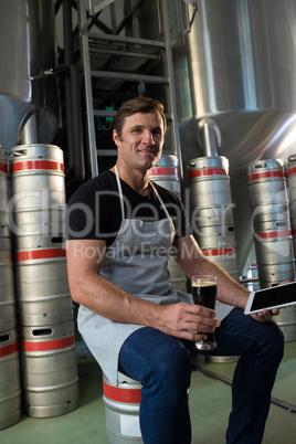 Portrait of smiling worker holding tablet and beer at warehouse