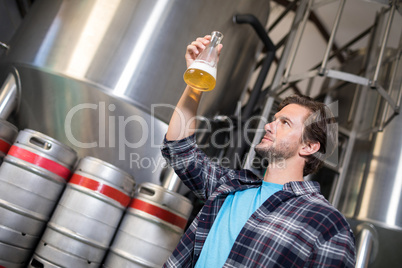 Low angle view of man examining beer in beaker