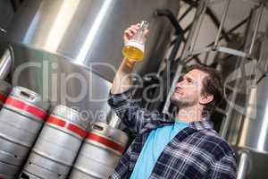 Low angle view of man examining beer in beaker