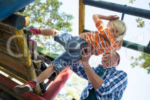 Low angle view of father assisting son in playing on jungle gym