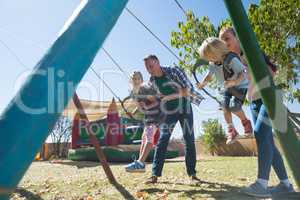 Playful parents swinging children at playground