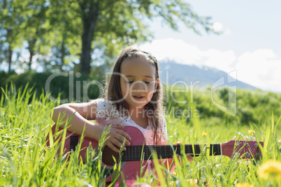 Cute girl playing guitar in field