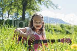 Cute girl playing guitar in field