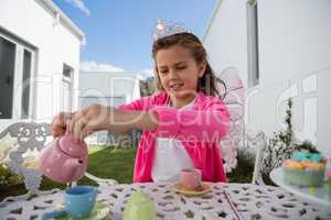 Girl in fairy costume pouring coffee into cup