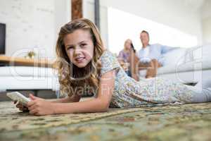 Daughter using digital tablet in living room while parents sitting on sofa