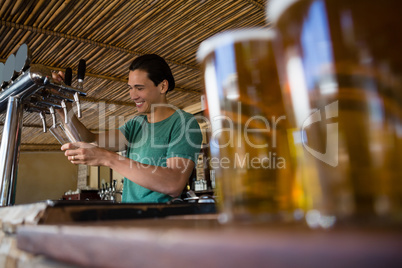 Close-up of beer glasses with bartender working at restaurant