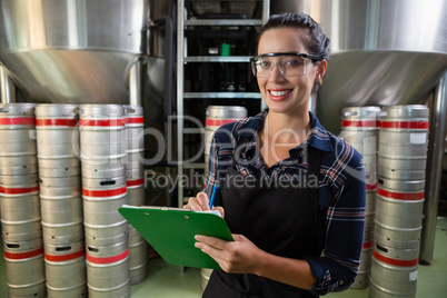 Portrait of smiling worker holding clipboard by storage tanks