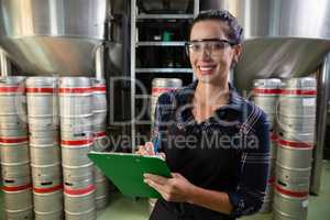 Portrait of smiling worker holding clipboard by storage tanks