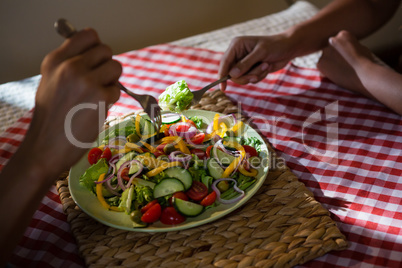 Cropped hands of friends having salad at table