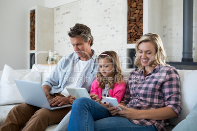 Family using laptop, digital tablet and mobile phone in living room