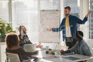 Male executive explaining business plans to his coworkers on flip chart