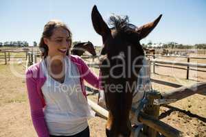 Smiling woman with horse at ranch