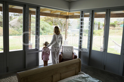 Mother and daughter standing with arms up at home