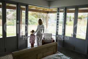 Mother and daughter standing with arms up at home