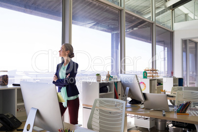 Female executive standing with arms crossed and looking at window