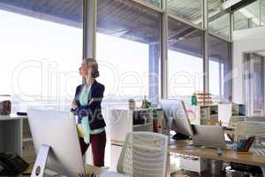 Female executive standing with arms crossed and looking at window