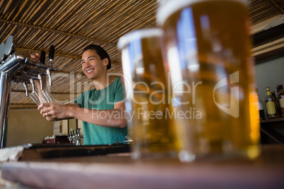 Close-up of beer glasses with bartender looking away