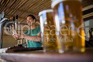 Close-up of beer glasses with bartender looking away