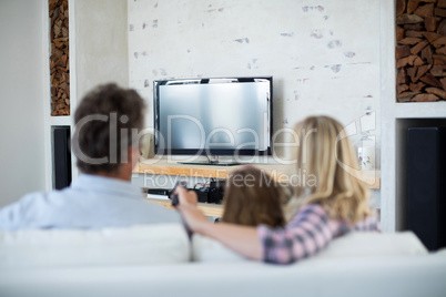 Family watching television in living room