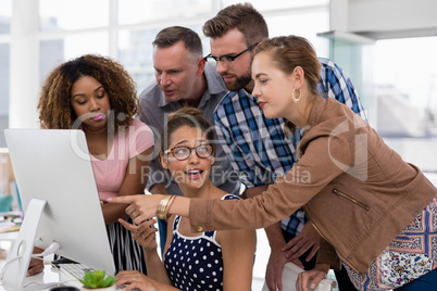 Team of executives discussing over computer in the office