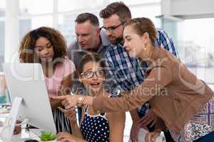 Team of executives discussing over computer in the office