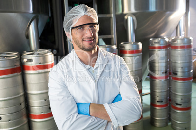 Portrait of worker standing by kegs at warehouse