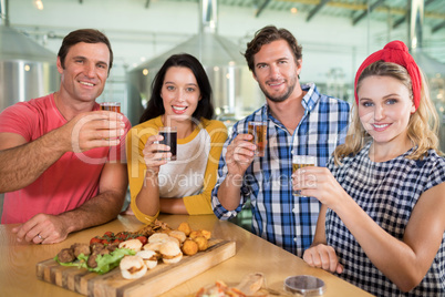 Portrait of happy friends holding beer glass in restaurant