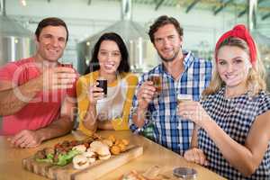 Portrait of happy friends holding beer glass in restaurant
