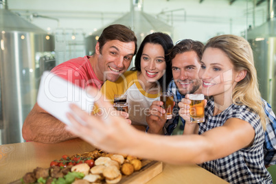 Woman taking selfie through mobile phone with friends in restaurant