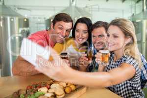 Woman taking selfie through mobile phone with friends in restaurant