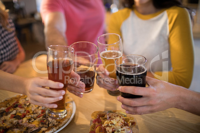 Cropped hands of friends toasting drinks in restaurant