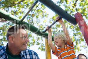 Low angle view of father and son playing on jungle gym